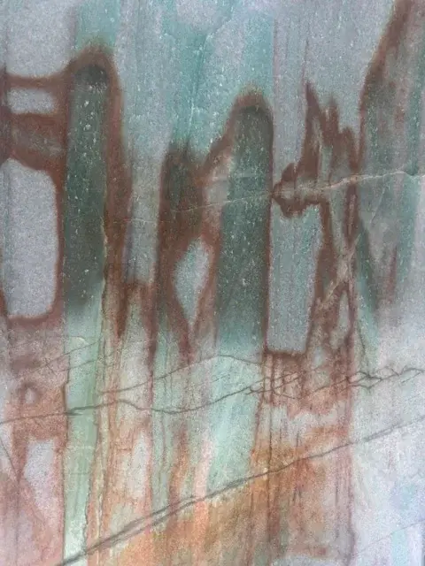 Close-up of green and gray stone veined with rust brown, a color reference for the mural